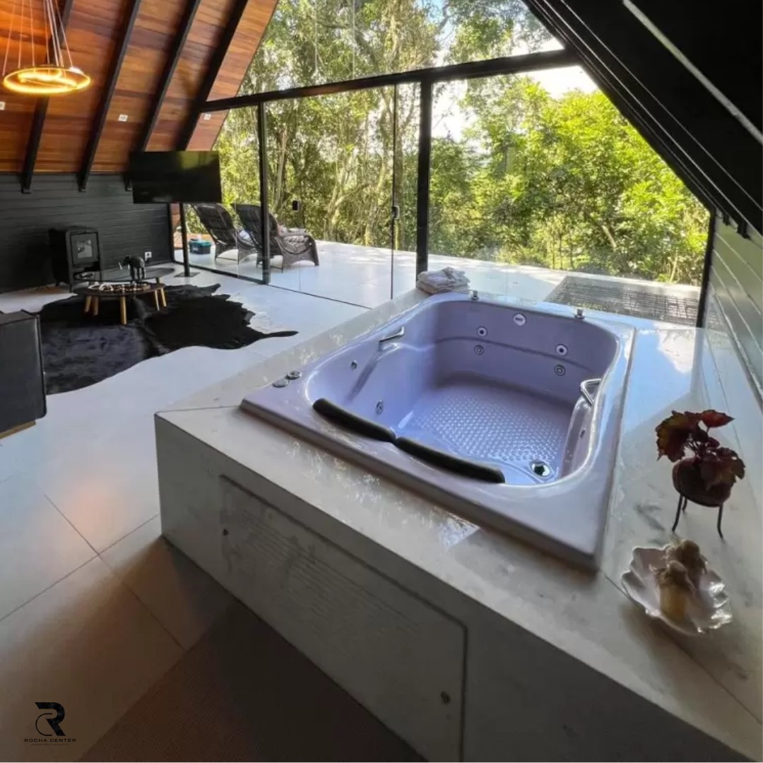 Uma foto de uma casa de luxo com um jacuzzi no meio do átrio, rodeado por janelas grandes com vista para a floresta